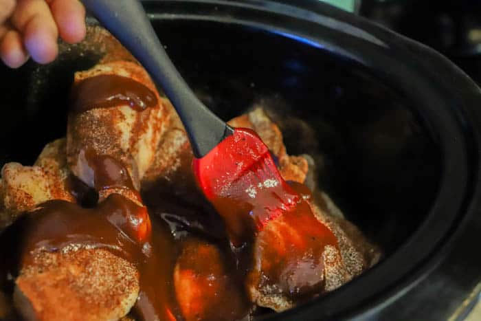 brushing bbq sauce on the Slow Cooker BBQ Chicken Legs