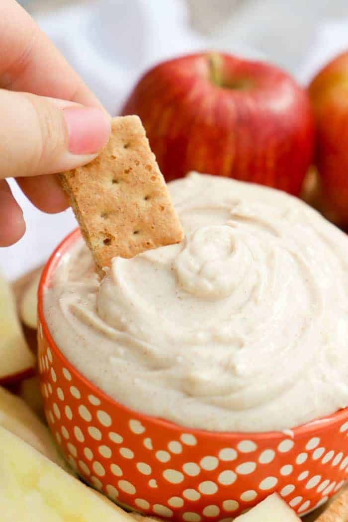 Snickerdoodle Dip dipping with a cracker