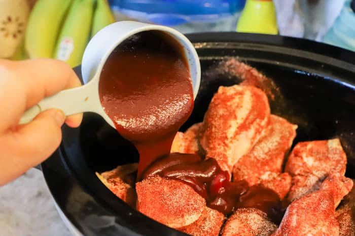 pouring sauce on the Slow Cooker BBQ Chicken Legs