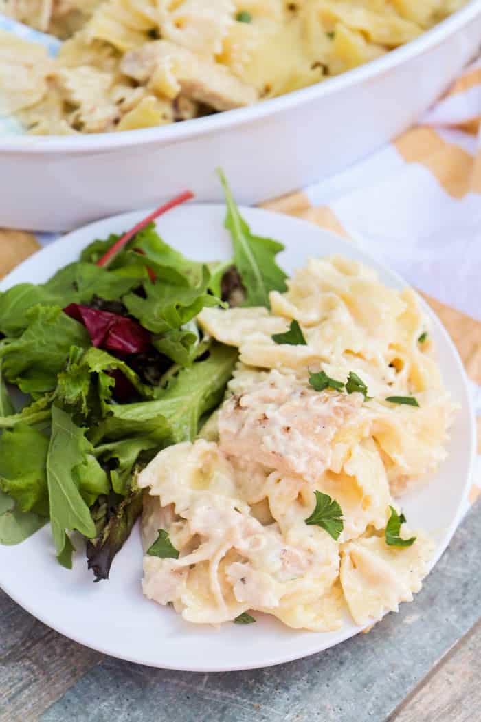 Chicken Alfredo Casserole on a white plate with a side salad