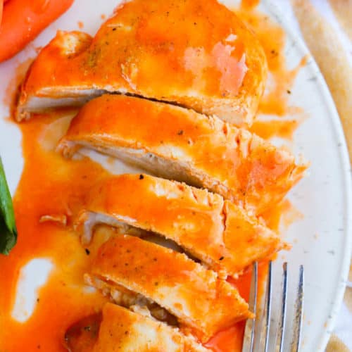Baked Buffalo Chicken on a white plate cut up to serve