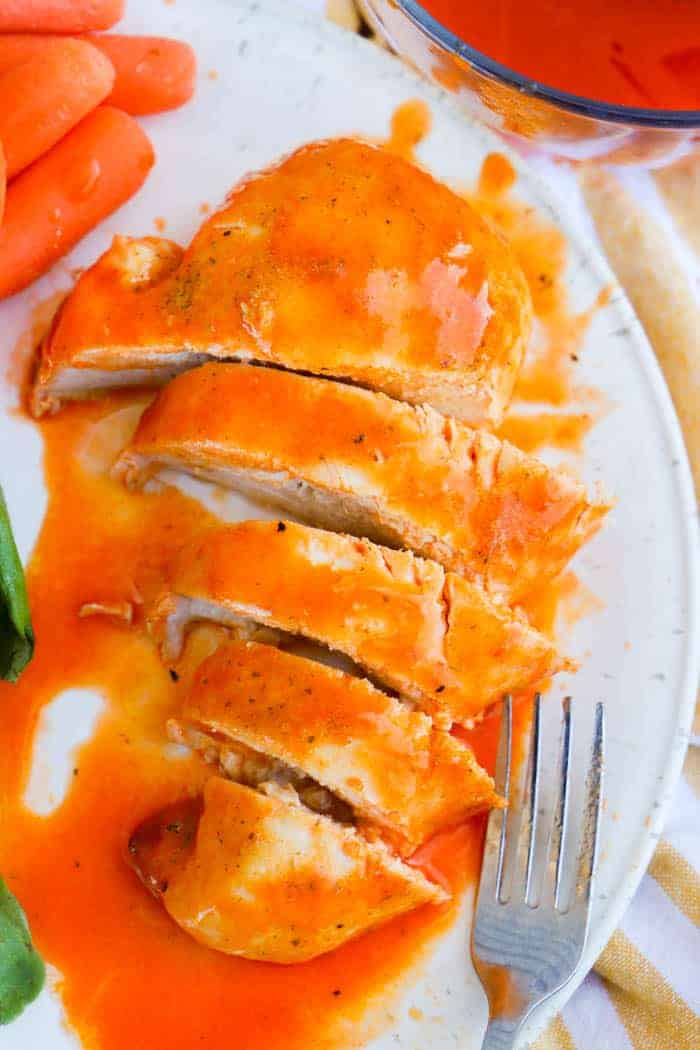 Baked Buffalo Chicken on a white plate cut up to serve