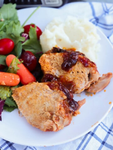 Slow Cooker Cranberry Pork Loin on a plate with salad and mashed potatoes