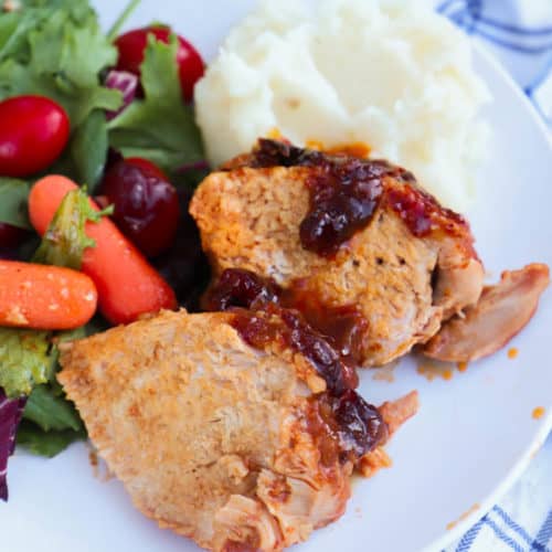 Slow Cooker Cranberry Pork Loin on a plate with salad and mashed potatoes