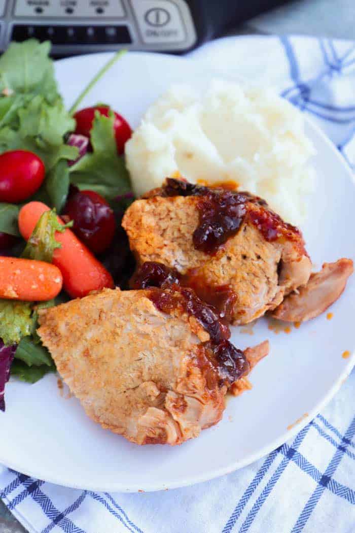 Slow Cooker Cranberry Pork Loin on a plate with salad and mashed potatoes