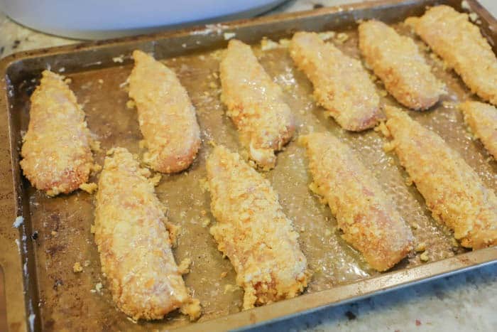 uncooked and breaded chicken on a baking sheet