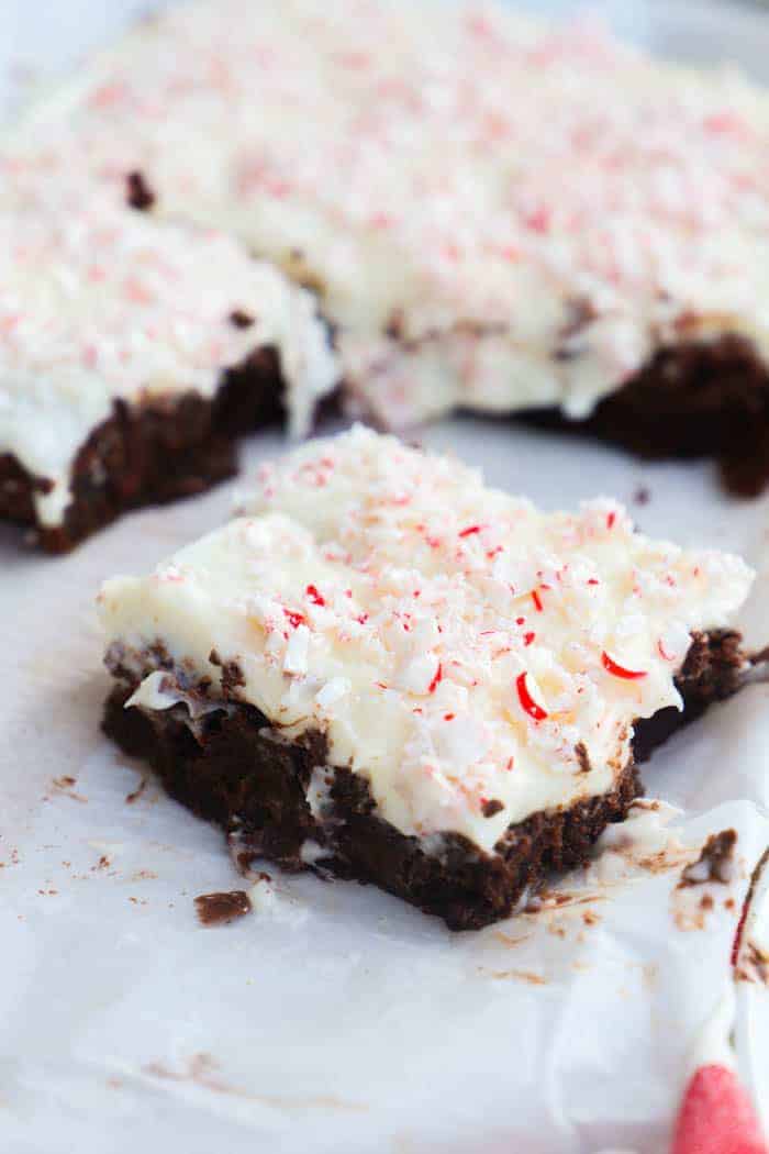 sliced Peppermint Cream Cheese Frosted Brownies on parchment paper