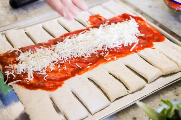 adding sauce and cheese to the Hawaiian Pizza Braid