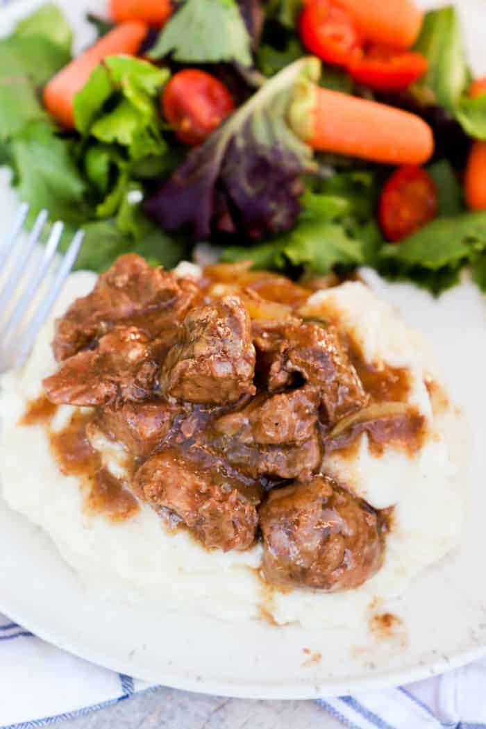 Slow Cooker Beef Tips on a white plate on mashed potatoes