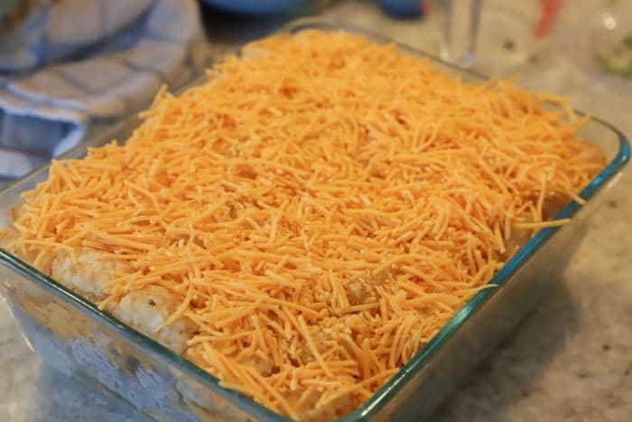 Tater Tot Bacon Cheeseburger Casserole topped with cheese and ready for the oven.