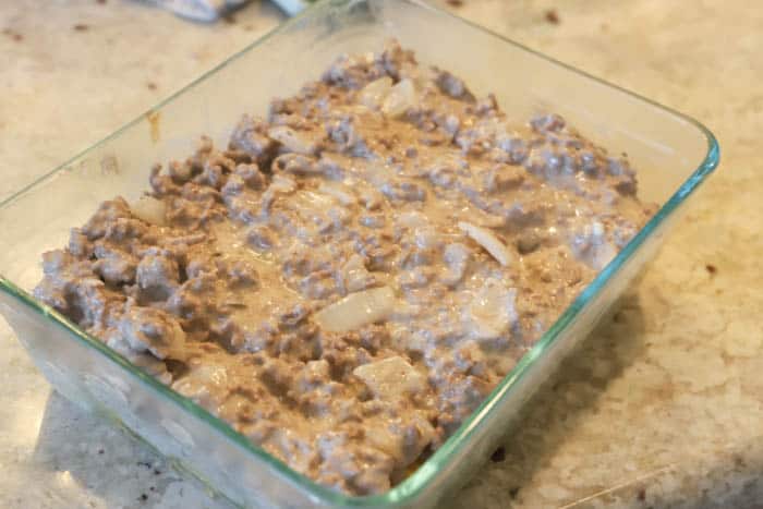 Tater Tot Bacon Cheeseburger Casserole base added to a clear casserole dish.