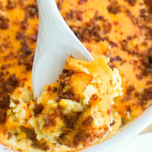Bacon and Corn Casserole in a casserole dish on a wooden spoon