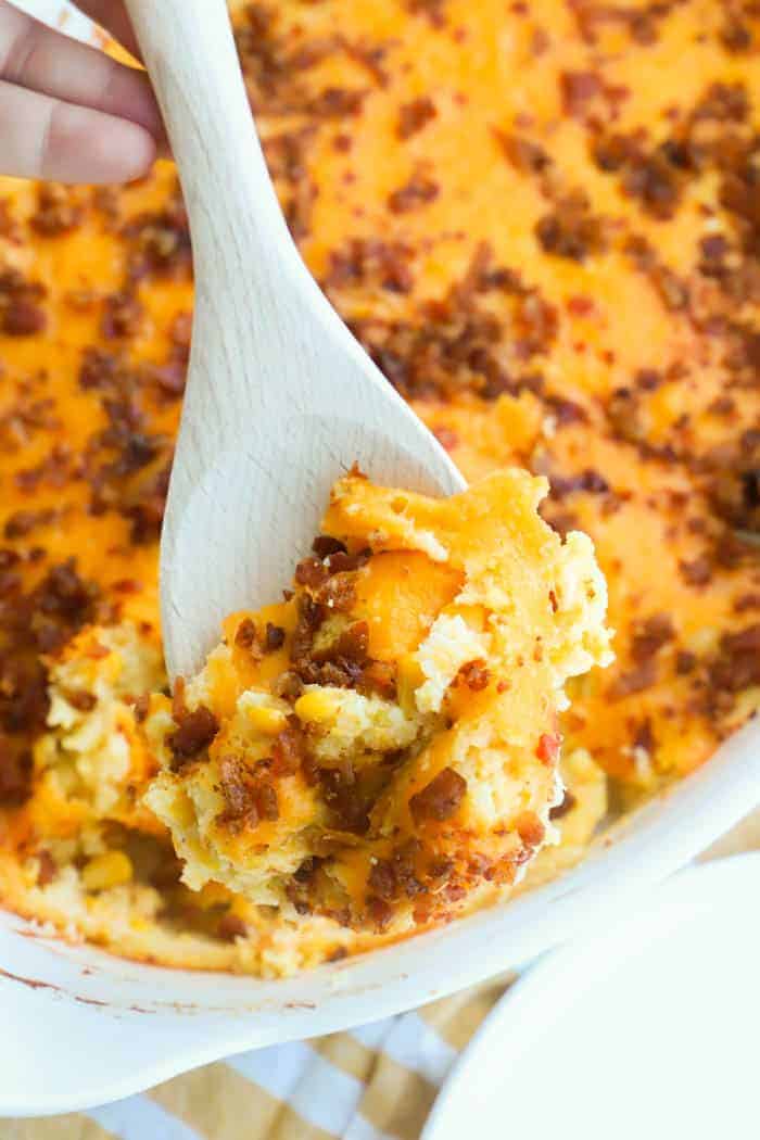 Bacon and Corn Casserole in a casserole dish on a wooden spoon