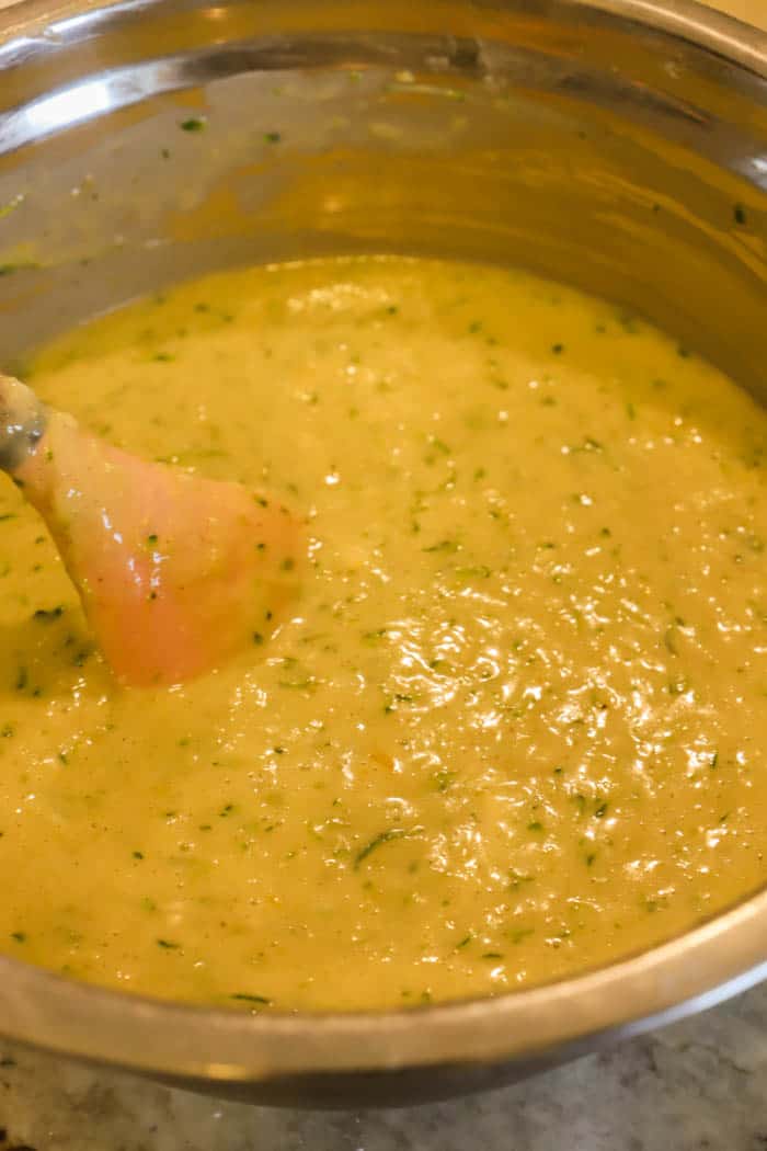 mixing dough in metal mixing bowl with pink spoon