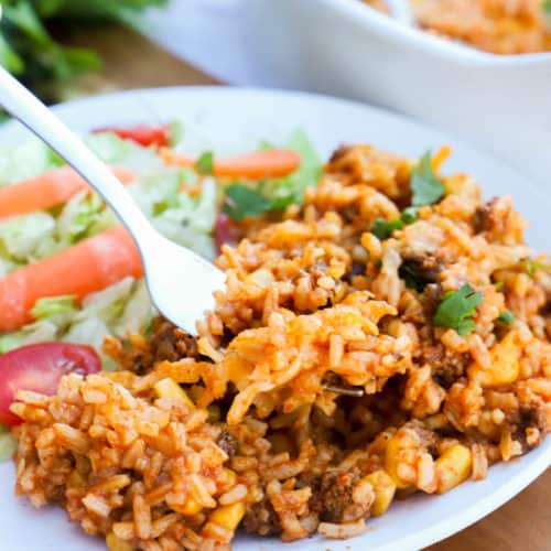 Beef Enchilada Casserole on a white plate with salad
