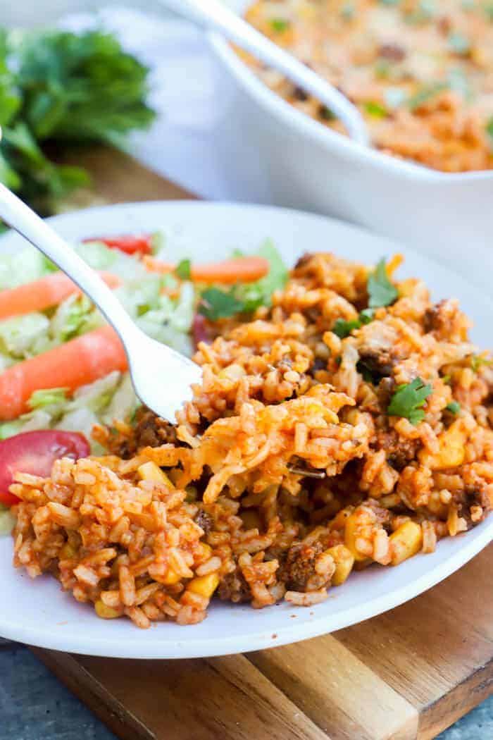 Beef Enchilada Casserole on a white plate with salad