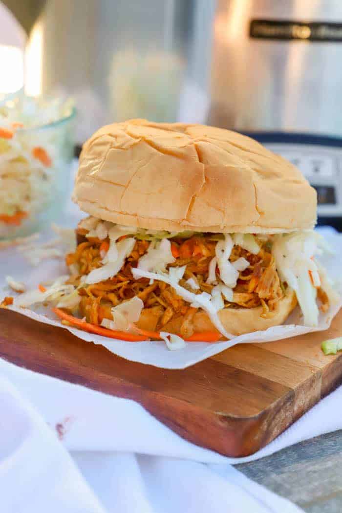 Slow Cooker Shredded Asian Chicken Sandwich on a wooden serving dish