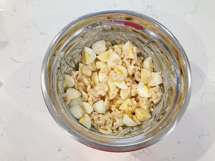 adding eggs to pasta salad.