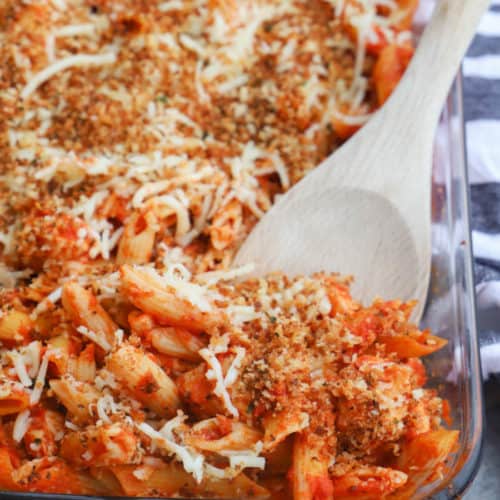 Chicken Parmesan Casserole in a casserole dish with a wooden spoon