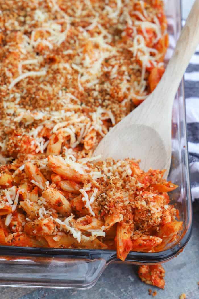 Chicken Parmesan Casserole in a casserole dish with a wooden spoon