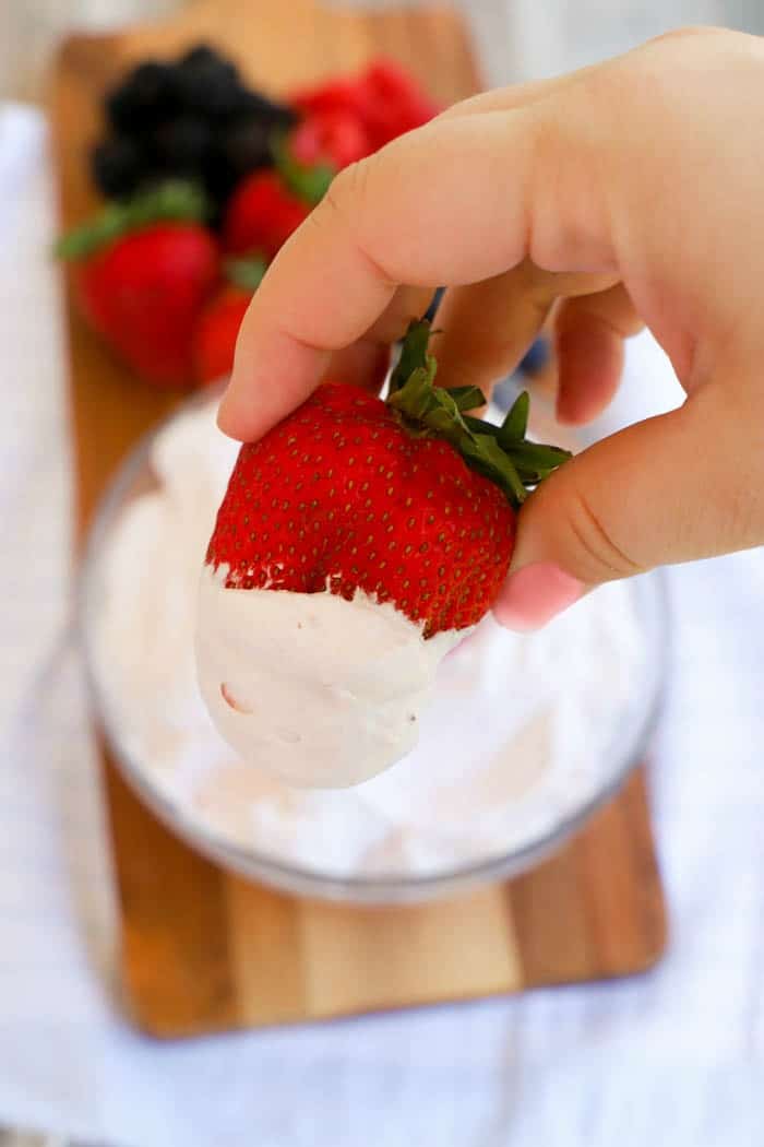 dipping a strawberry in Raspberry Fruit Dip 