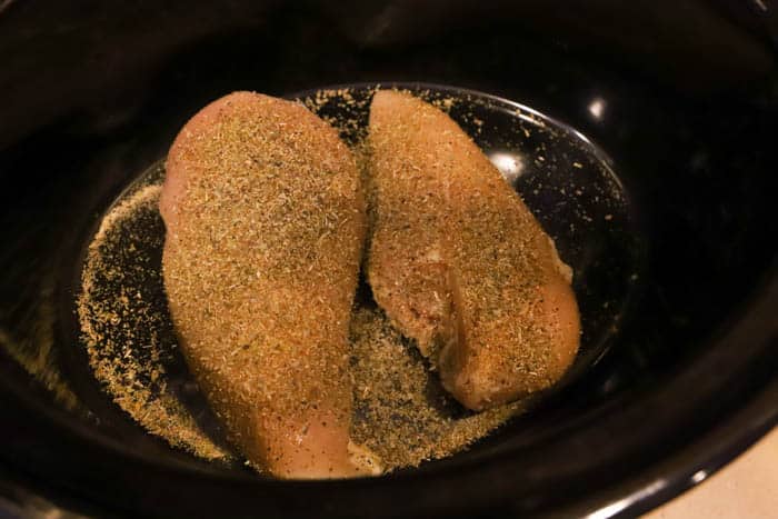adding chicken and seasoning in slow cooker
