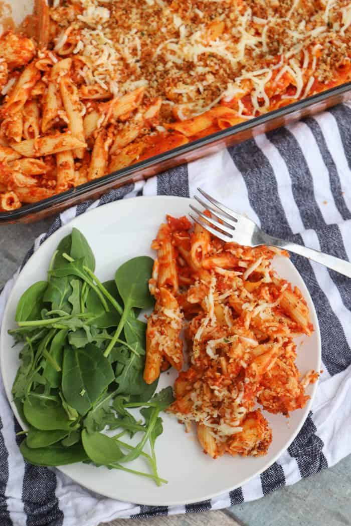 Chicken Parmesan Casserole on a white plate with salad