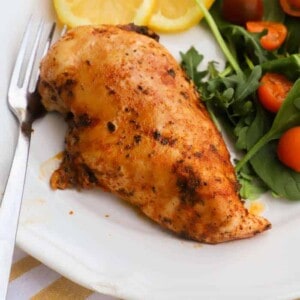 chicken marinade on a plate with salad and slice lemons
