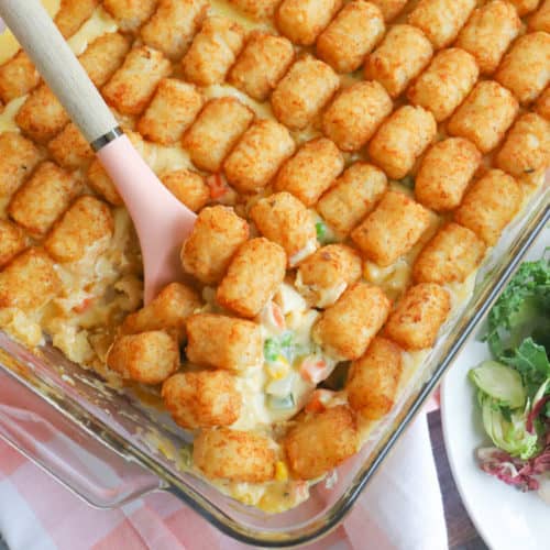tater tot casserole in a casserole dish with pink spoon