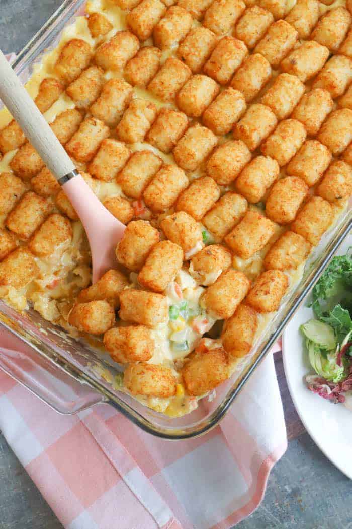 tater tot casserole in a casserole dish with pink spoon