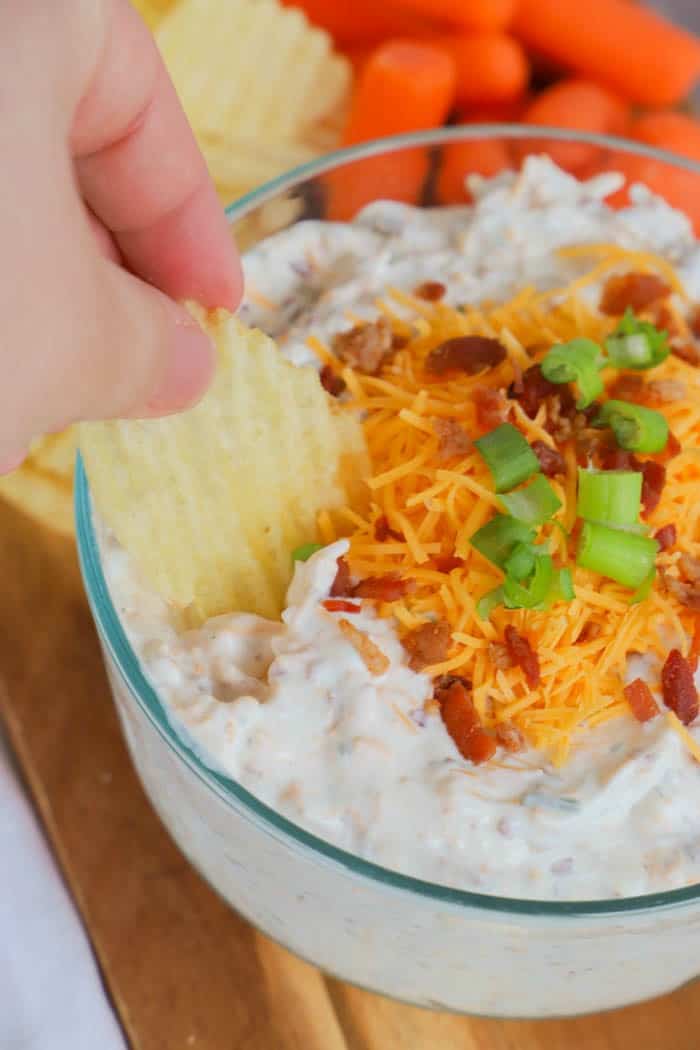 Loaded Ranch Dip dipping with a chip