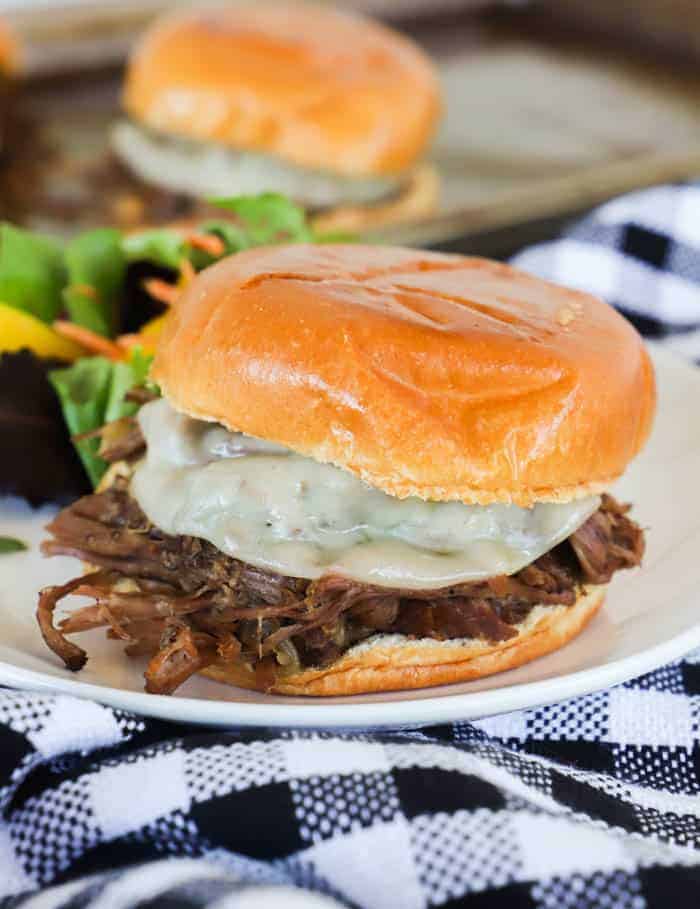 Slow Cooker Shredded Beef Sandwiches on a white plate with salad