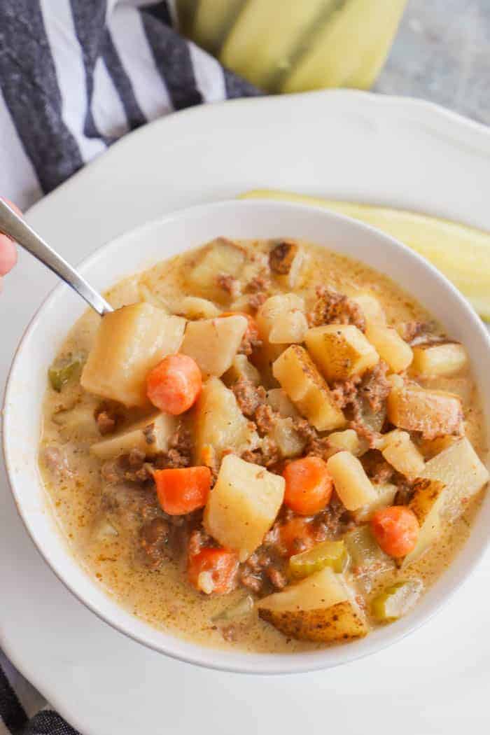Slow Cooker Cheeseburger Soup with silver spoon inside bowl