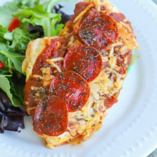 Pizza Stuffed Chicken on a white plate with a salad