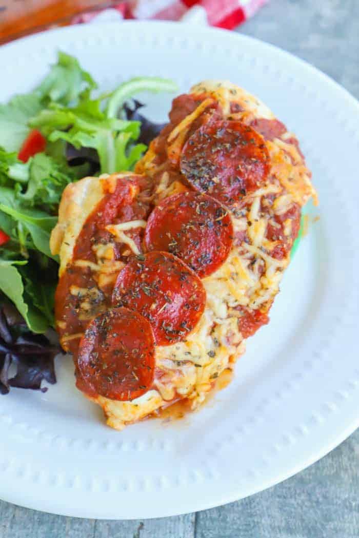 Pizza Stuffed Chicken on a white plate with a salad