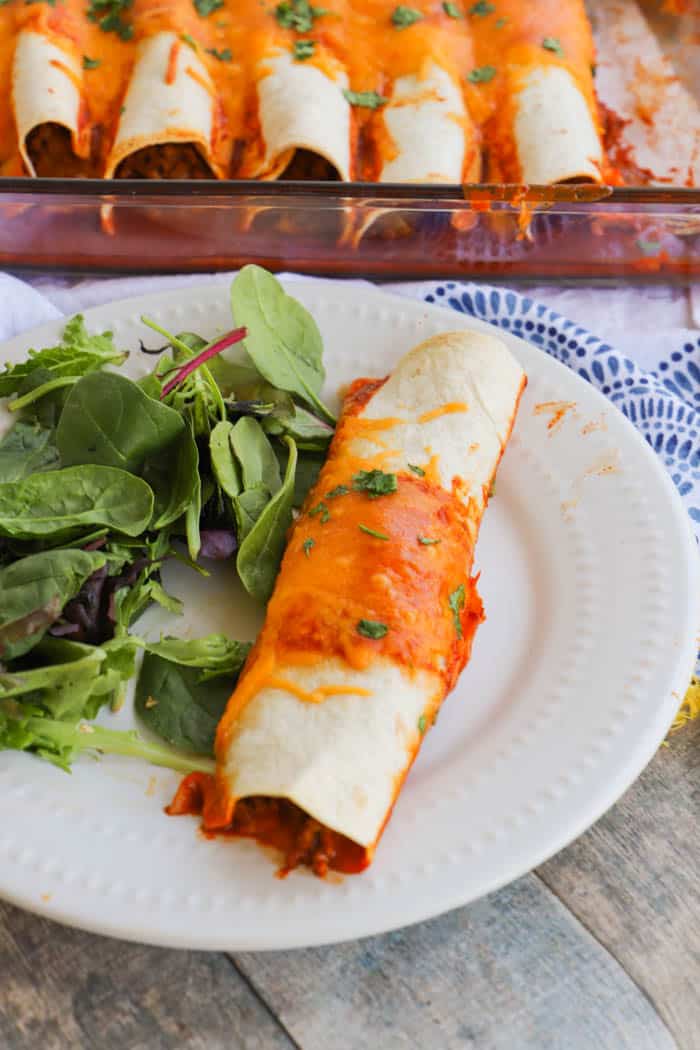 Easy Beef Enchiladas in a white plate with a salad on the side