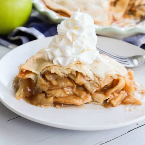 apple pie on a white plate with whipped cream