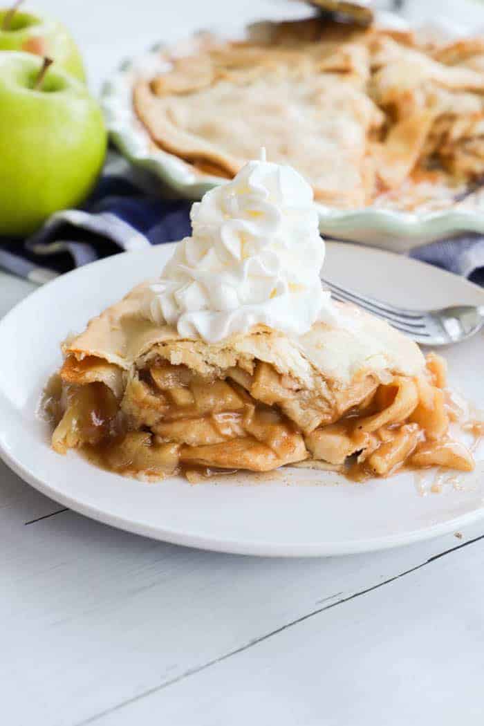 apple pie on a white plate with whipped cream