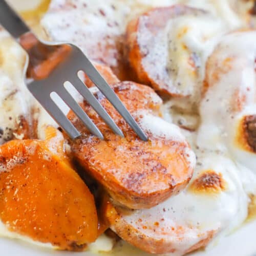 Candied Yams on a white plate with a fork with melted marshmallows