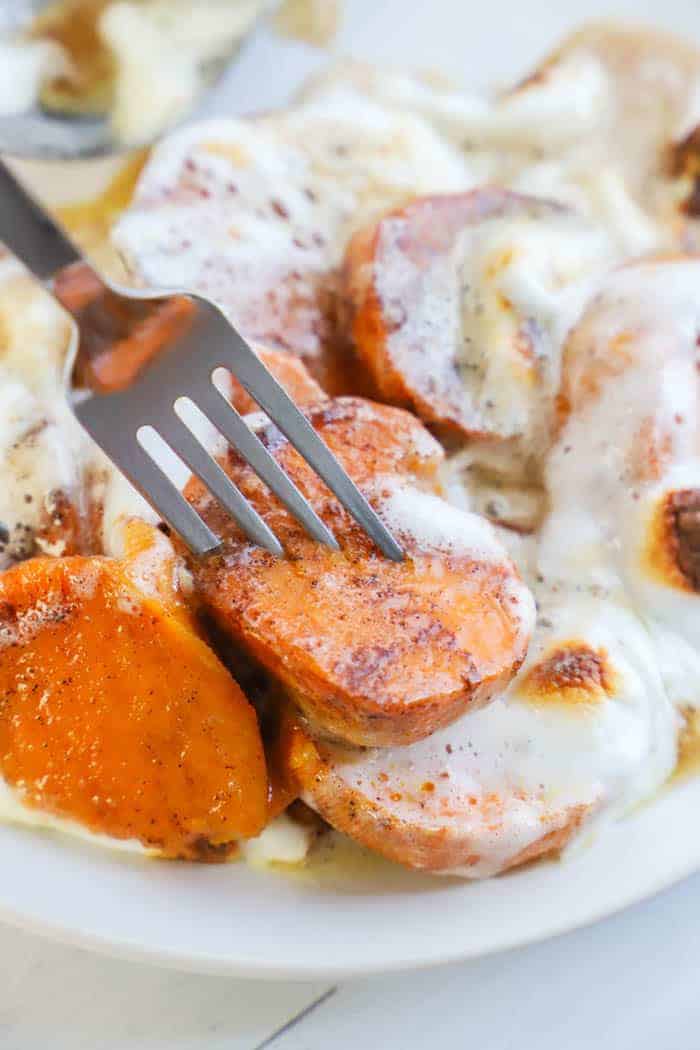 Candied Yams on a white plate with a fork with melted marshmallows