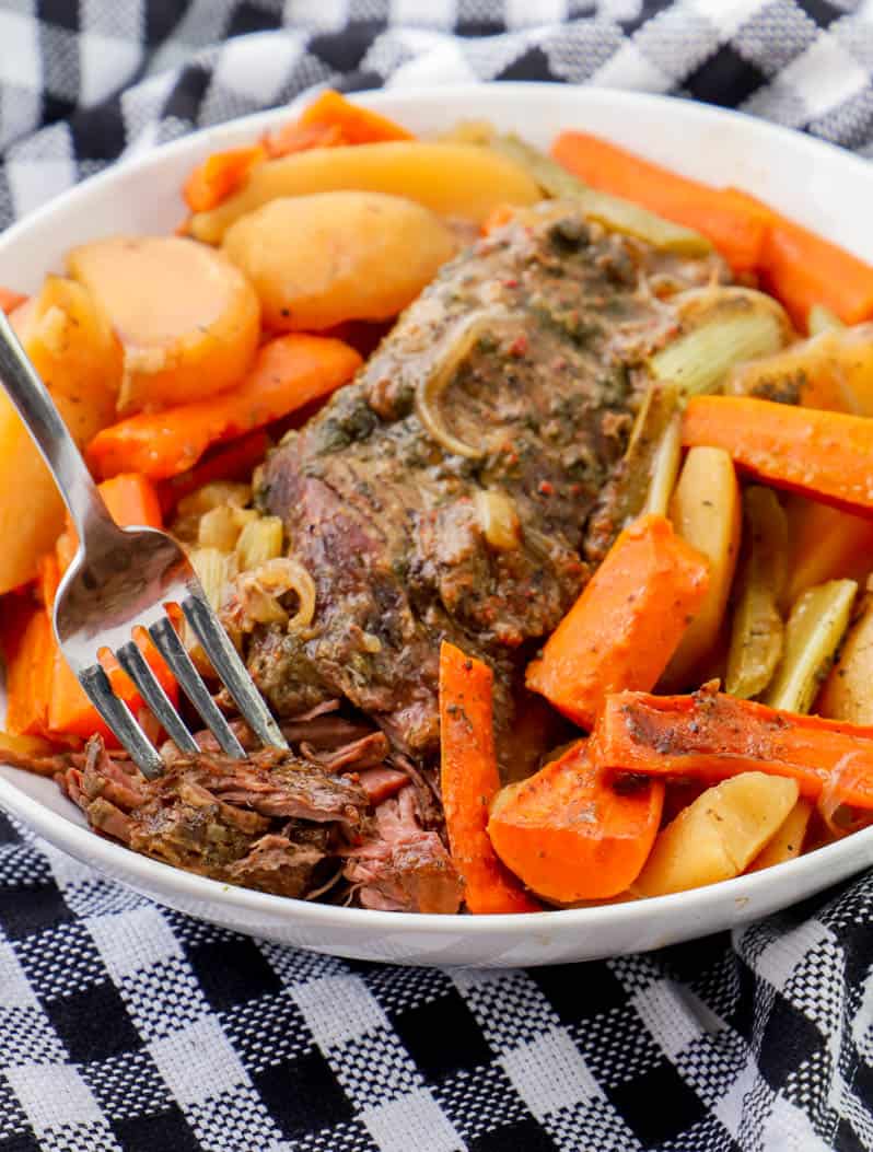 pot roast in a white bowl with veggies and a fork