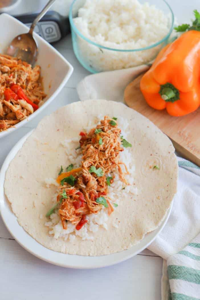 Chicken Fajitas on a soft tortilla with rice on white plate