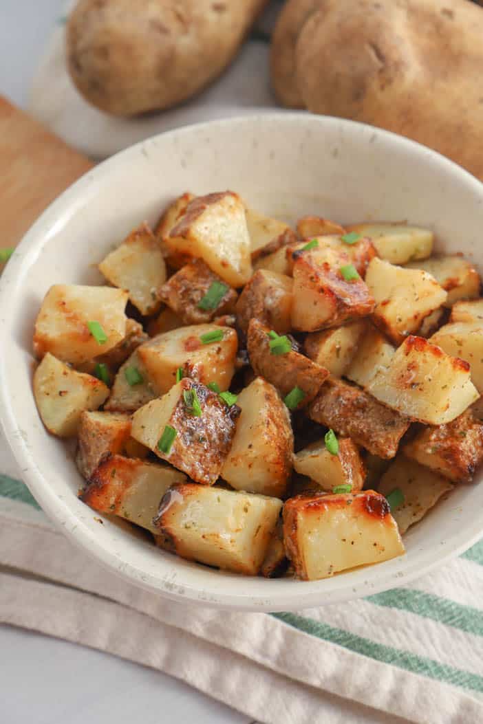 close up picture of potatoes in a bowl sprinkled with green chives