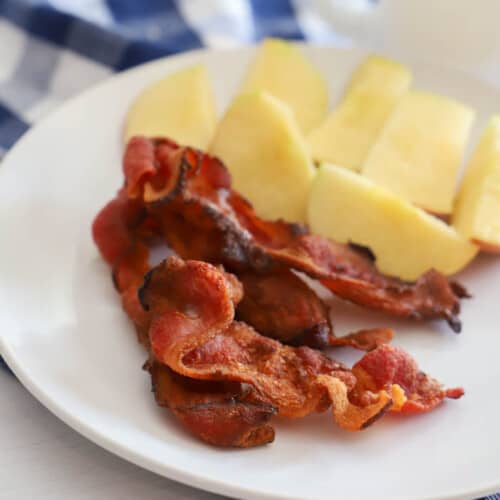 Air Fryer​ Bacon on a white plate with apples