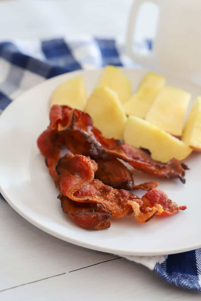 Air Fryer​ Bacon on a white plate with apples