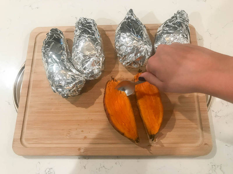 potatoes being cut open and insides scooped up