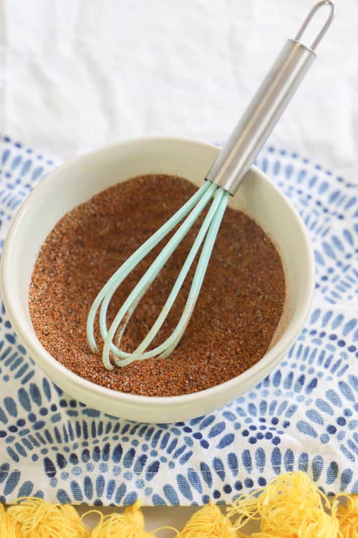 whisking all taco seasonings together in a white bowl