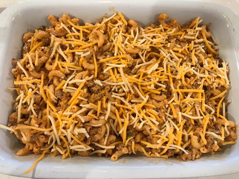 taco mac casserole in white casserole dish with shredded cheese