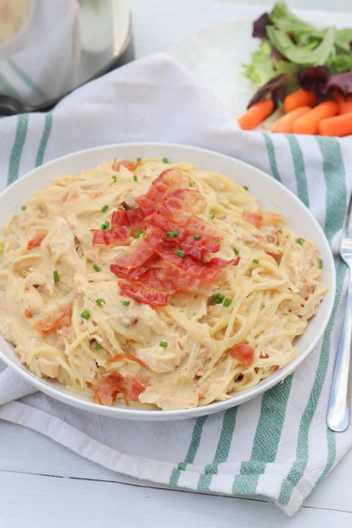 Slow Cooker Chicken Bacon Ranch Pasta in a white bowl and green napkin