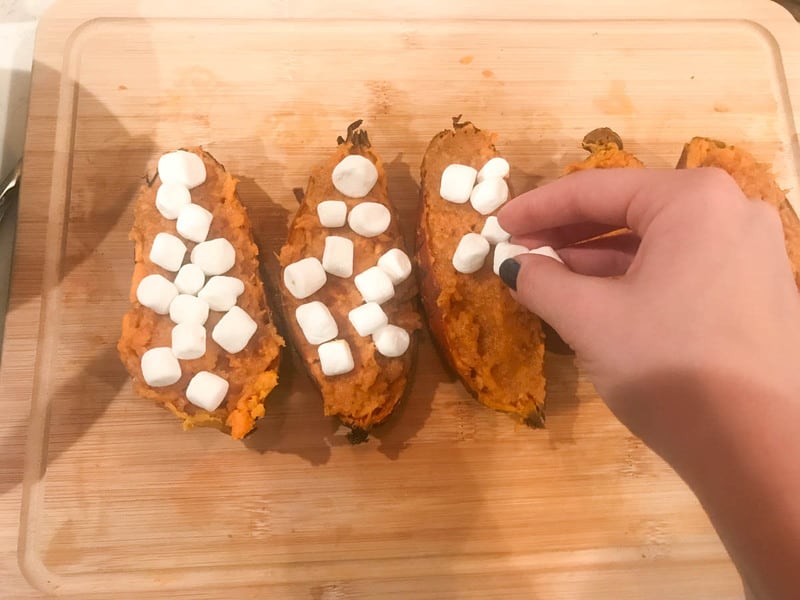 adding marshmallows to the top of the potatoes